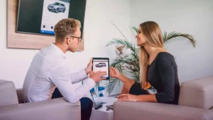 Vantagens do financiamento de veículos para a saúde financeira
homem e mulher conversando em uma sala vendo um carro em um tablet